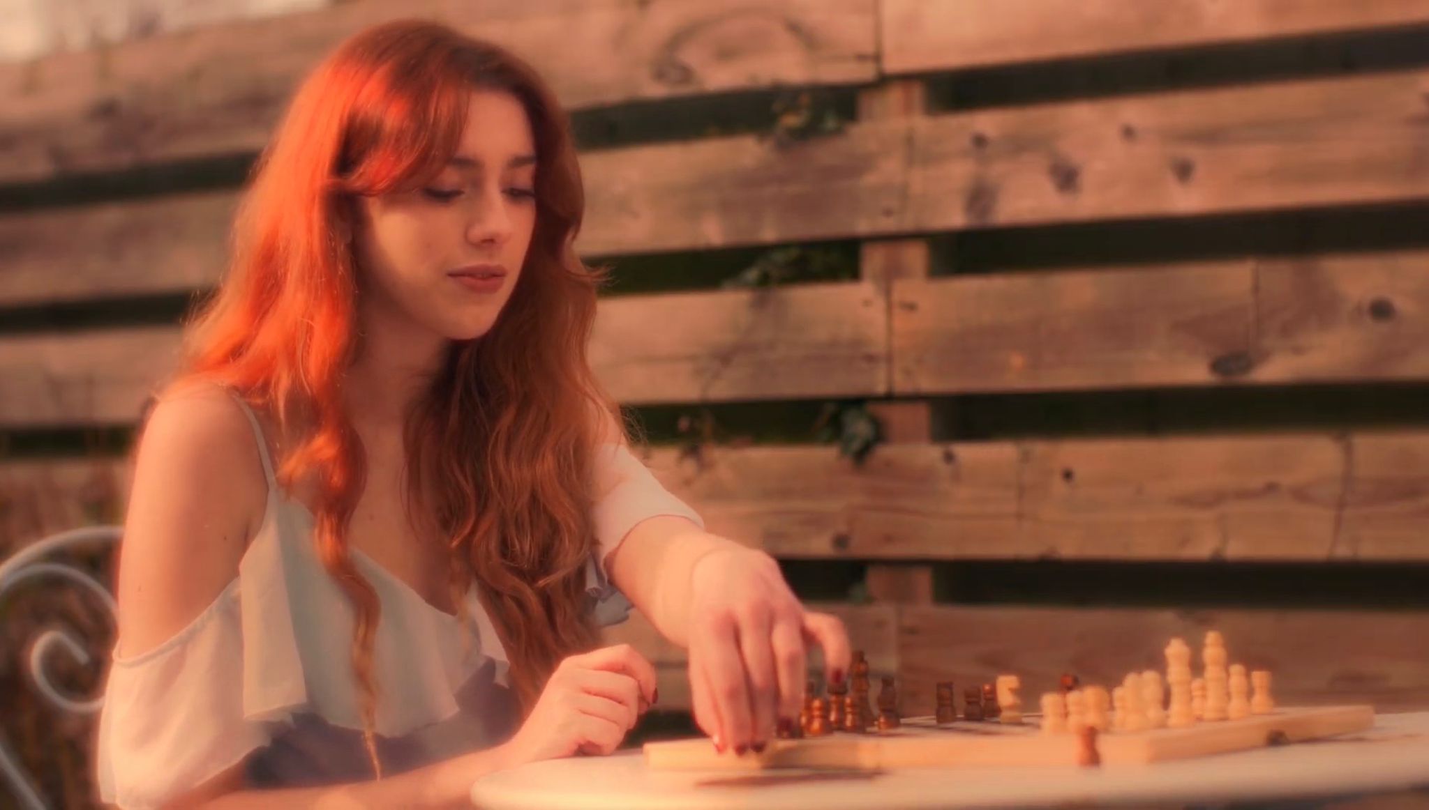 A woman thoughtfully moving a piece on a chessboard
